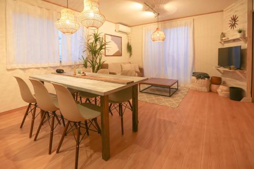 a dining room table and chairs in a living room at #オーシャンビューBBQ可能 #4LDK新築一軒家 #長期滞在歓迎 -- 時空間 凪 Nagi -- in Hyakuna