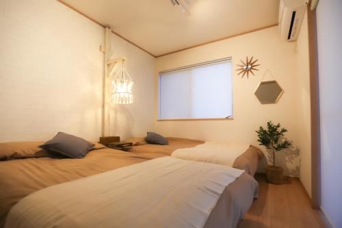 a bedroom with two beds and a window at #オーシャンビューBBQ可能 #4LDK新築一軒家 #長期滞在歓迎 -- 時空間 凪 Nagi -- in Hyakuna