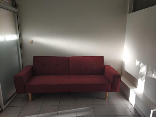 um sofá vermelho sentado no canto de uma sala em Mandariniers 97232-2 em Le Lamentin