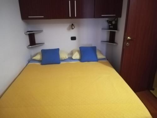 Casa Doina في بايلي فيليكس: غرفة نوم بسرير اصفر ومخدات زرقاء
