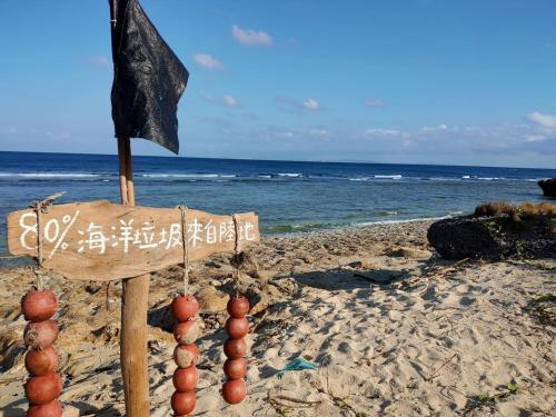 a wooden sign on a beach with a flag at 南海之醉旅店 in Xiaoliuqiu