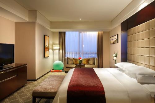 ein Hotelzimmer mit einem großen Bett und einem TV in der Unterkunft The QUBE Hotel Shanghai -Close to Pudong International Airport and Disney Land in Shanghai