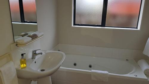 uma casa de banho com um lavatório e uma banheira em Tudor Lodge Motel em Hawera