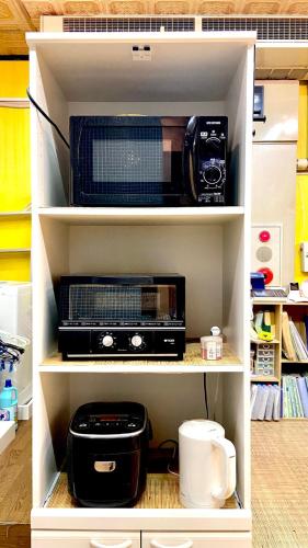 a kitchen shelf with a microwave and a toaster oven at Hostel Furoya in Osaka