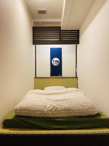 a bed in a small room with a blue and white at Hostel Furoya in Osaka