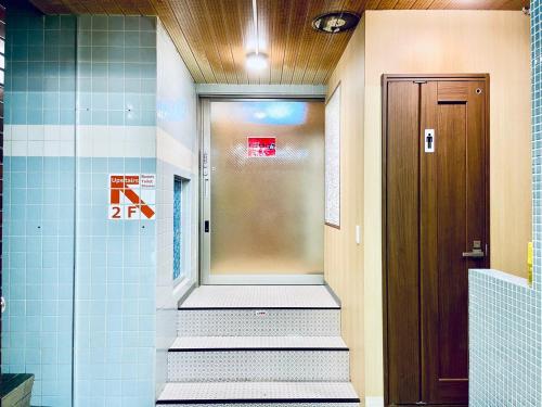 a hallway with a door and stairs in a bathroom at Hostel Furoya in Osaka