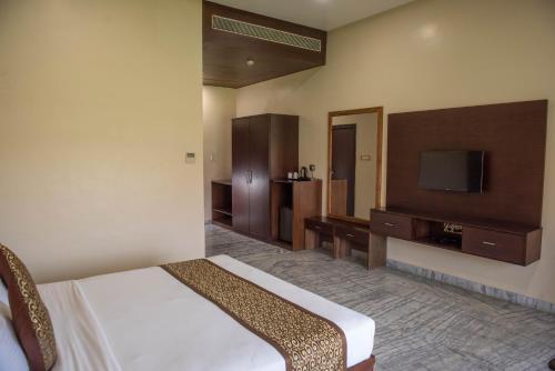 a hotel room with a bed and a flat screen tv at Sun Hotel and Resort, Mount Abu in Ābu Road