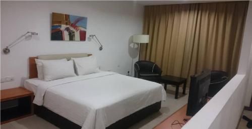 a bedroom with a bed and a television in it at Gloria Swiss Hotel & Apartment Sandakan in Sandakan