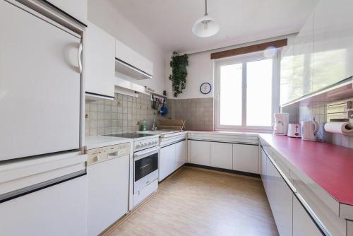 a kitchen with white cabinets and a large window at Sunny Apartment in Vienna