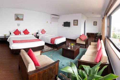 a hotel room with two beds and chairs at Dhulikhel Mountain Resort in Dhulikhel
