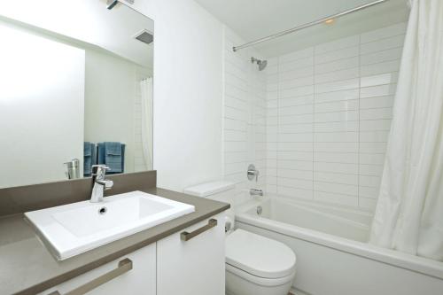 a white bathroom with a sink and a toilet at Gorgeous Old Town Condo with Patio and Parking! in Victoria