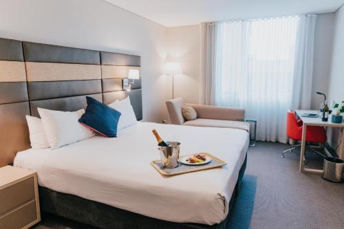 a hotel room with a bed with a tray of food on it at Novotel Newcastle Beach in Newcastle