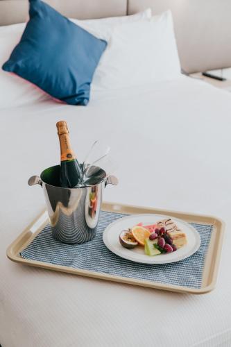 a tray with a bottle of champagne and a plate of food at Novotel Newcastle Beach in Newcastle