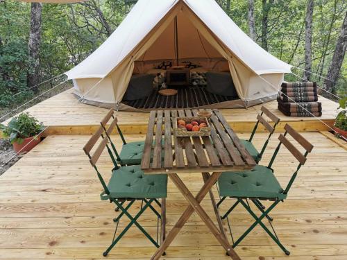 Šmarje的住宿－ECO Camp Supot，木甲板上的桌椅和帐篷