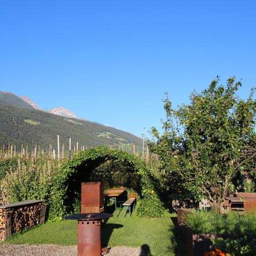 a garden with an arch and a table and chairs at Haus im Erlengrund in Coldrano