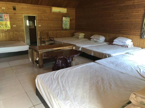 a room with three beds and a table in it at Liu Fu Shan Zhuang in Kenting