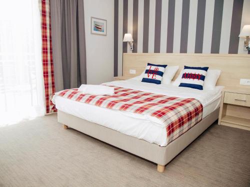 Schlafzimmer mit einem Bett mit einer roten und weißen Decke in der Unterkunft Porto Marina in Krynica Morska
