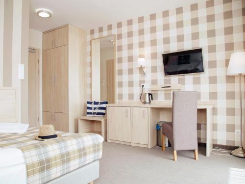 Schlafzimmer mit einem Bett, einem Schreibtisch und einem TV in der Unterkunft Porto Marina in Krynica Morska