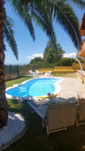 einen Pool mit zwei Stühlen und einer Palme in der Unterkunft Terrazza sul golfo degli angeli in Capitana