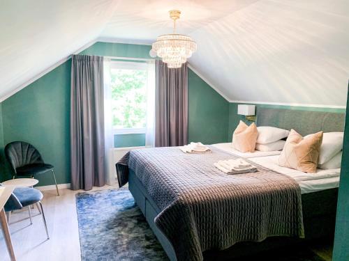 um quarto com uma cama grande e um lustre em Drottning Victorias Hotell & Vilohem em Borgholm