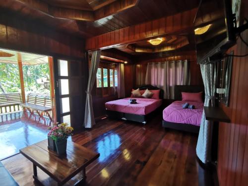 a living room with two beds and a table at Walk in homestay in Ko Kood