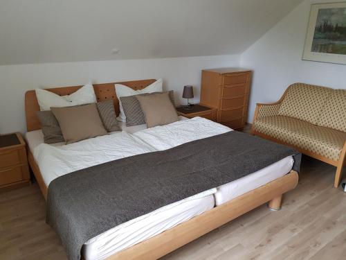 a bedroom with a large bed and a chair at Ferienwohnung Am Lindenkrog in Rickert