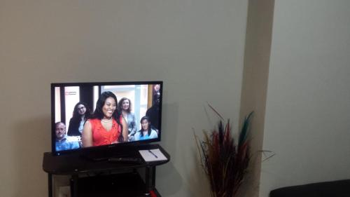 una pantalla de TV con un grupo de personas en ella en Hotel Amor Rosebank, en Johannesburgo
