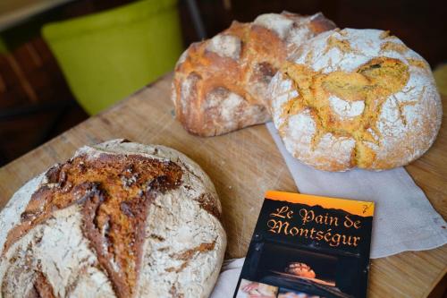 Saint-Paul-de-JarratにあるLe Clos Cathala Chambres d'Hôtesの木のテーブルの上に本が置かれたパン2斤