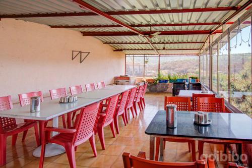 a dining room with tables and red chairs at Shilpa Strawberry Garden in Mahabaleshwar