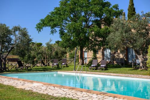 a swimming pool in a yard with chairs and trees at Azienda Agrituristica Le Chiuse in Manciano