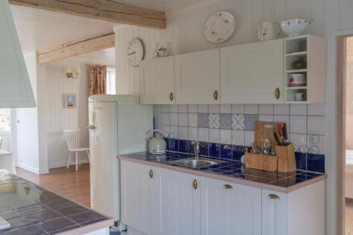 una cocina con armarios blancos y fregadero en Roose City House, en Kärdla