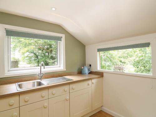 a kitchen with a sink and two windows at Shilstone Lodge in Newton Abbot