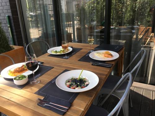 a wooden table with plates of food and glasses of wine at Bulvar Hotel in Gorzów Wielkopolski