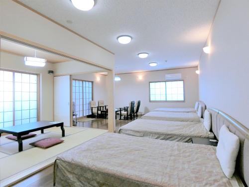 宮崎市にある民宿inn みやざき湯楽庵のベッド3台とテーブルが備わる部屋