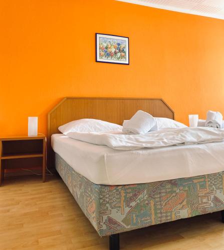 a bed in a room with an orange wall at Hotel Auerhahn in Grevenkrug
