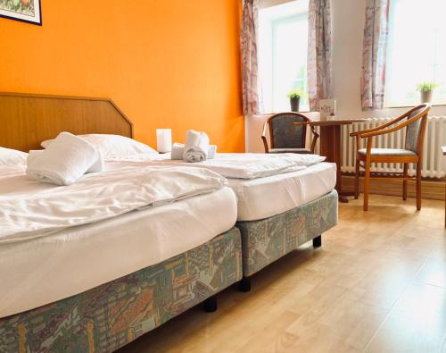two twin beds in a room with orange walls at Hotel Auerhahn in Grevenkrug