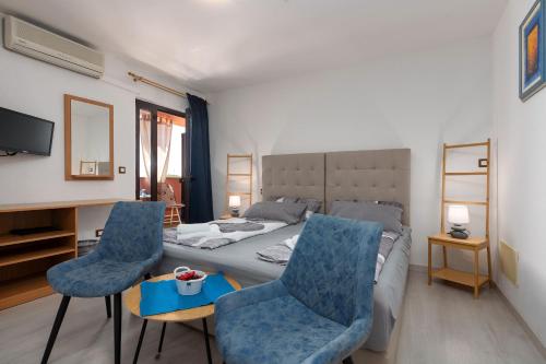 a bedroom with a bed and two blue chairs at Apartments Miri Vrsar in Vrsar