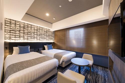 a hotel room with two beds and a table and chairs at Quintessa Hotel Sapporo Susukino in Sapporo