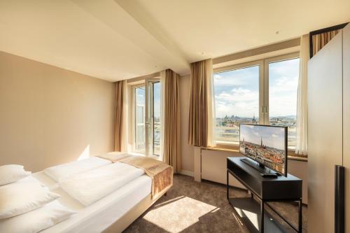 um quarto de hotel com uma cama e uma televisão de ecrã plano em Hotel Am Parkring em Viena