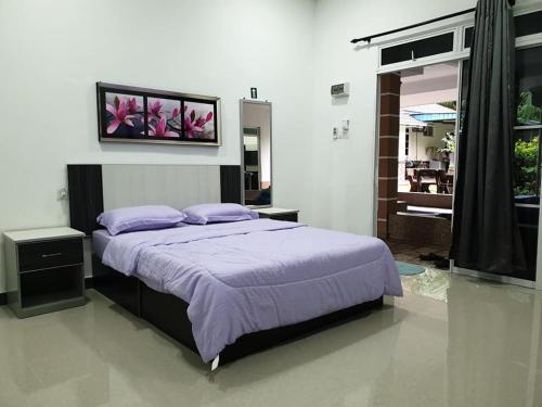 - une chambre avec un grand lit et des oreillers violets dans l'établissement Inapdesa Teratak Bonda, Sepri REMBAU, à Rembau