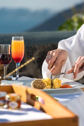 a couple eating food on a table with wine glasses at Adamant Suites in Fira