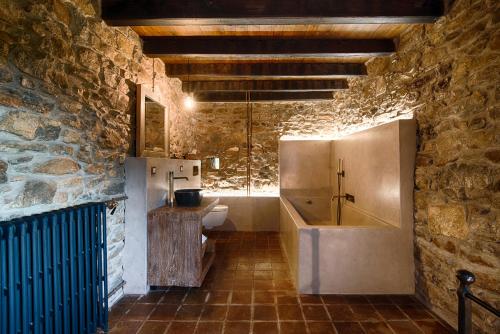 a stone bathroom with a sink and a tub at Masia Can Pou in Canet de Adri