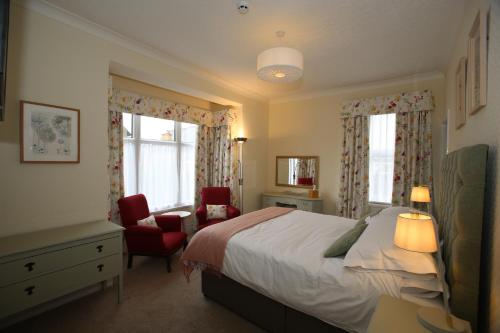 a bedroom with a bed and a chair and two windows at The Cordelia in Scarborough