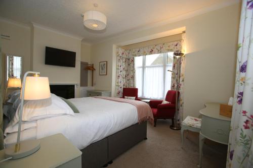 um quarto com uma cama grande e uma cadeira vermelha em The Cordelia em Scarborough