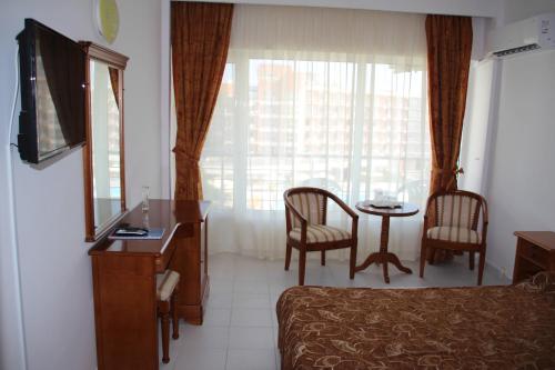 Habitación de hotel con cama y mesa con sillas en Hotel Orfeu, en Mamaia