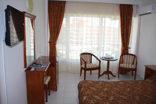 a hotel room with a bed and a table with chairs at Hotel Orfeu in Mamaia