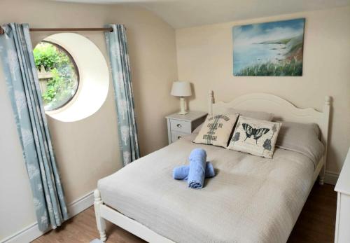 un osito de peluche azul sentado en una cama en un dormitorio en The Coach House Douglas, en Cork