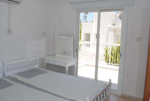Dieses weiße Zimmer verfügt über 2 Betten und ein Fenster. in der Unterkunft Flisvos Beach Apartments in Protaras