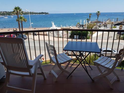 uma mesa e cadeiras numa varanda com vista para a praia em Les marines Agay em Agay - Saint-Raphaël