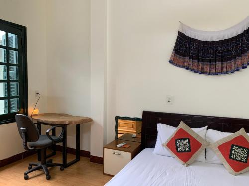 Schlafzimmer mit einem Bett, einem Schreibtisch und einem Stuhl in der Unterkunft Be's Home & Tours in Ha Giang